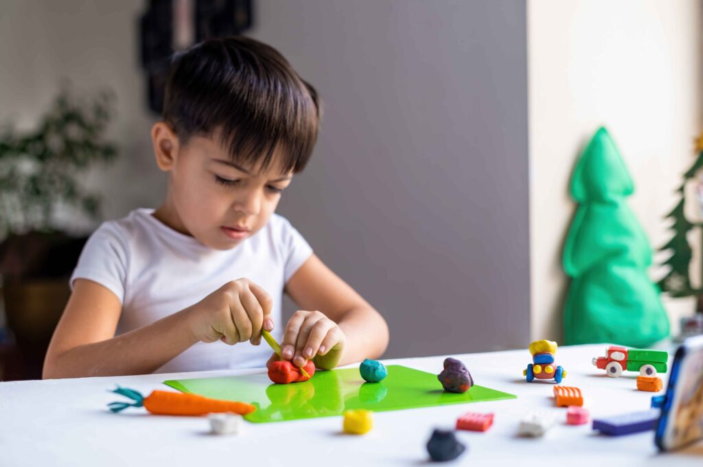 small-caucasian-boy-playing-with-colored-plasticine-making-figures-white-table-happy-child-idea (1) learning with figures
